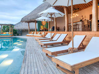 Infinity-Pool und Sonnenliegen vor dem offenen Haupthaus 